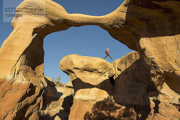 Ein junges Mädchen wandert am Rand des Metate Arch im Devil's Garden  Hole in the Rock Road  Grand Staircase-Escalante National Monument  Escalante  Utah.