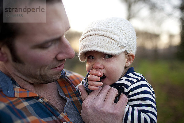 Ein Vater hält seine kleine Tochter im Arm und tröstet sie  während sie weint.