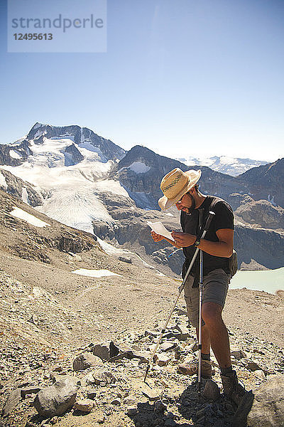 Ein Wanderer hält an  um hoch oben in den Bergen über dem Wedgemount Lake im Garibaldi Provincial Park den Weg zu lesen.