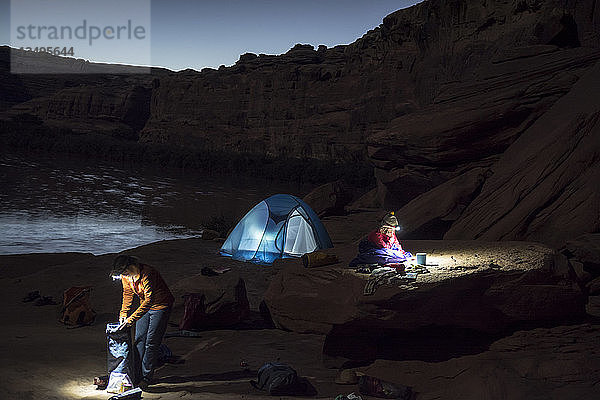 Eine Mutter und ihre Tochter machen sich in einem Zelt bettfertig  während sie auf Sandstein entlang des Labyrinth Canyon-Abschnitts des Green Rivers  Green River  Utah  zelten.