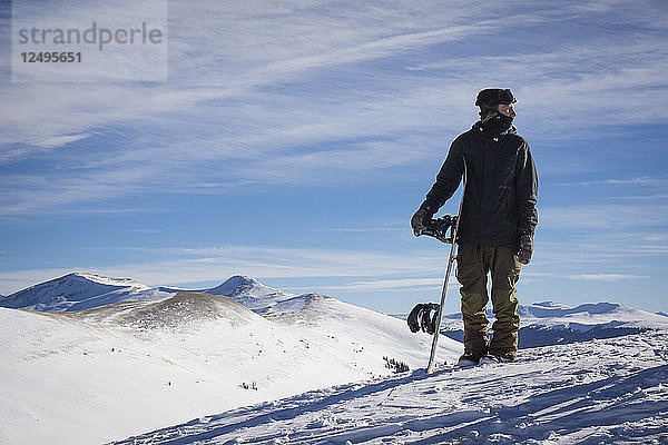 Snowboarder auf dem Gipfel eines Berges stehend