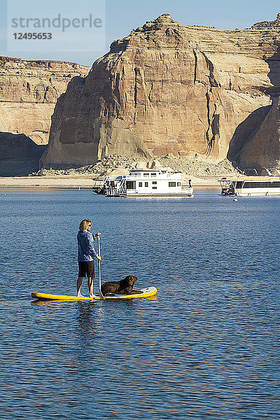 Eine Frau und ihr Hund paddeln auf dem Lake Powell  Wahweap Marina  Glen Caynon National Recreation Area  Page  Arizona.