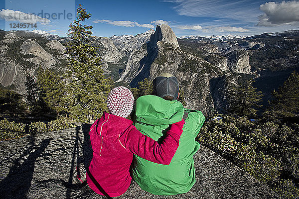 Ein Paar macht am Glacier Point eine Pause  um den Half Dome im Yosemite National Park zu betrachten.
