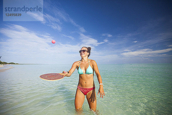 Eine junge Frau spielt während ihres Urlaubs in Cayo Coco  Kuba  mit einer Strandversion von Racquetball.