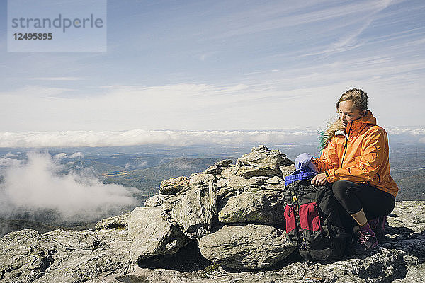 Weiblicher Wanderer mit Rucksack auf Felsen sitzend in Mount Mansfield