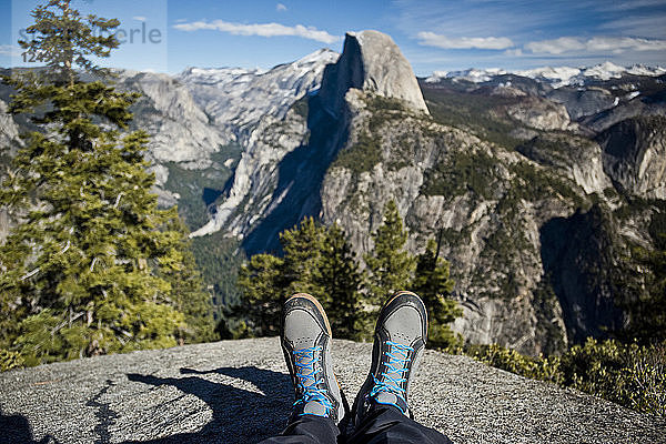 Die Stiefel eines Wanderers sind während einer Pause mit dem Half Dome im Hintergrund im Yosemite National Park zu sehen.