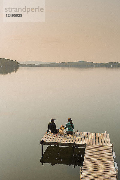 Blick auf Mann und Frau mit Hund sitzen am Rande des Docks auf Kaspischen See