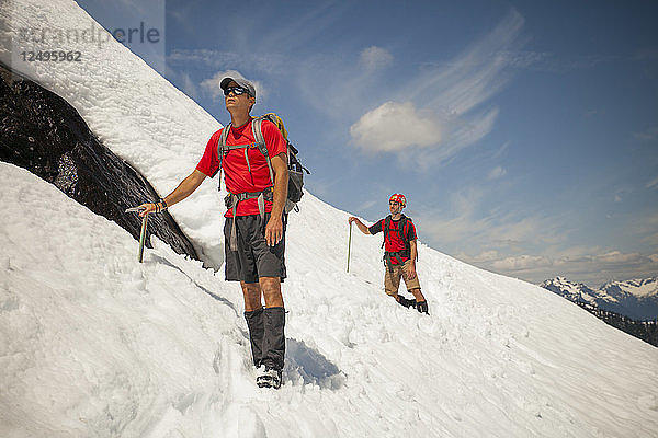 Zwei Bergsteiger überqueren ein Schneefeld hoch in den Bergen von British Columbia  Kanada.