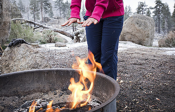 Ein Mädchen wärmt sich an einem Wintertag in Big Bear  CA  die Hände am Feuer.