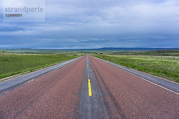 Rote Straße in der Mitte von Wyoming mit Märchenwolken