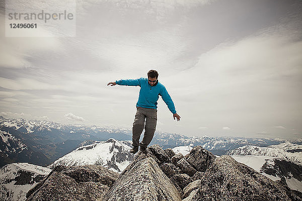 Ein Wanderer balanciert auf einem Granitfelsen auf dem Gipfel des Needle Peak.