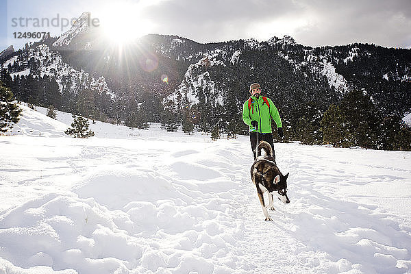 Ein Mann und sein Hund gehen an einem sonnigen Wintertag durch den Chautauqua Park in Boulder  Colorado.