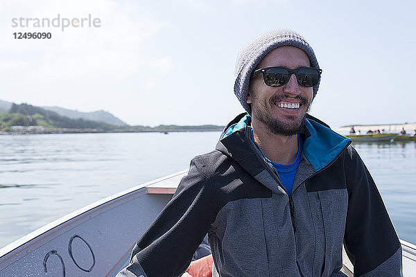 Junger männlicher Erwachsener lächelt während der Fahrt in einem kleinen Krabbenkutter an der Küste von Oregon