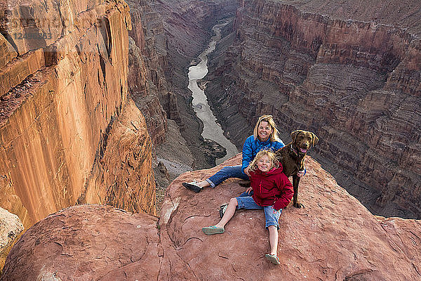Eine Mutter  eine Tochter und ihr Hund sitzen am Rande des Toroweap Overlook über dem Colorado River  Grand Canyon National Park  Fredonia  Arizona.