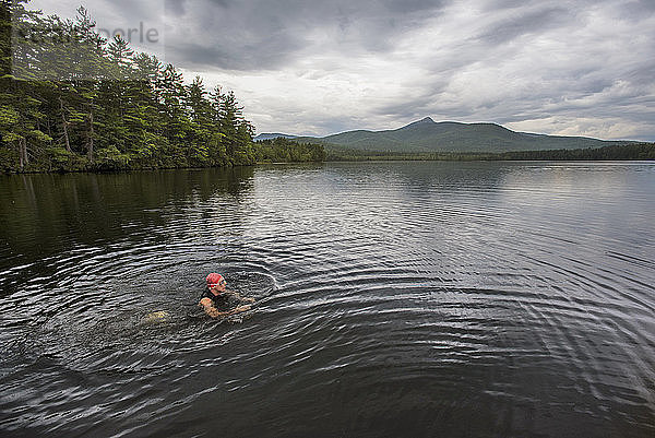 Ein Schwimmer  der an einem bewölkten Tag eine Pause im flachen Wasser macht