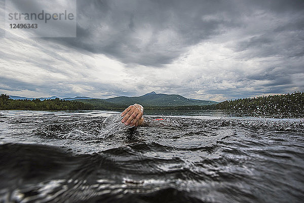 Die Hand eines Schwimmers  der beim Schwimmen im See aus dem Wasser gezogen wird