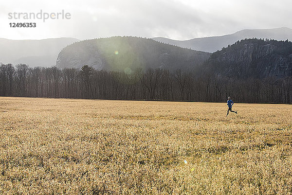 Lone Läufer in einem Feld mit Wolken und Berge im Hintergrund