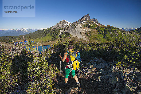 Ein Fotograf fotografiert eine junge Frau  die mit dem Rucksack auf dem Panorama Ridge Trail unterwegs ist  mit dem Black Tusk Mountain im Hintergrund im Garibaldi Provincial Park  British Columbia  Kanada.