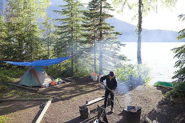 Eine Frau kümmert sich beim Zelten im Bowron Lake Provincial Park  British Columbia  Kanada  um ein Feuer.