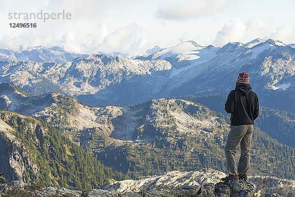 Ein Wanderer blickt von einem felsigen Grat im Pinecone Burke Provincial Park in British Columbia  Kanada  auf eine wunderschöne Berglandschaft.