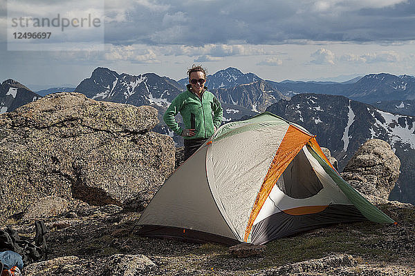 Eine Rucksacktouristin steht neben ihrem Zelt beim Zelten im Cathedral Lakes Provincial Park  British Columbia  Kanada.