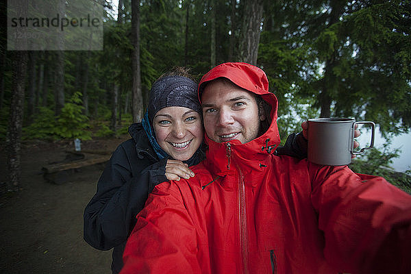 Ein Paar macht ein Selfie an einem regnerischen Tag beim Camping im Bowron Lake Provincial Park.