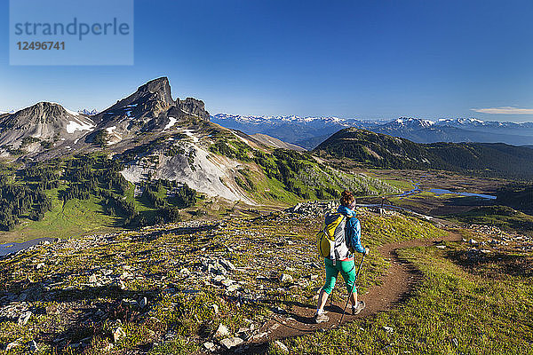Eine junge Frau wandert mit dem Rucksack auf dem Panorama Ridge Trail mit dem Black Tusk Mountain im Hintergrund im Garibaldi Provincial Park  British Columbia  Kanada.