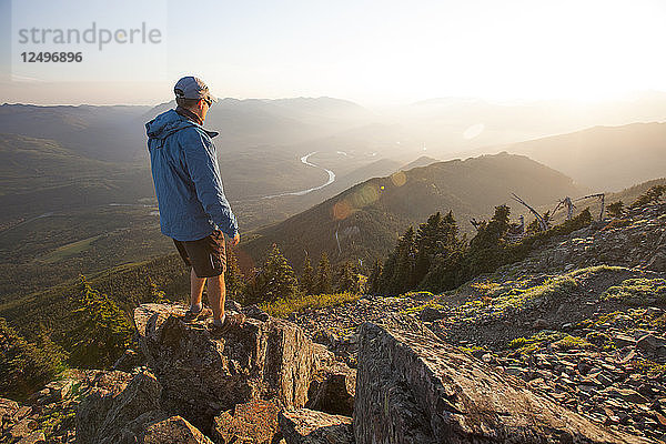 Ein Wanderer blickt vom Gipfel des Sauk Mountain in der North Cascade Mountain Range  Washington  auf das Skagit Valley und den Fluss hinunter.