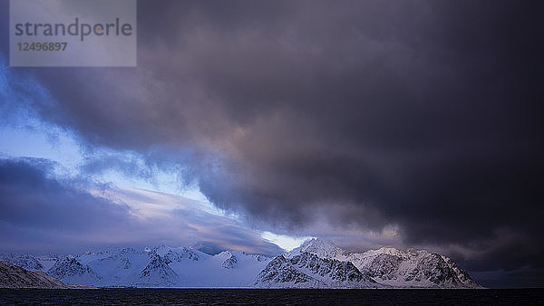 Schwarzes Eismeer im Vordergrund mit Schnee und Rocky Mountains im Hintergrund bei Sonnenaufgang