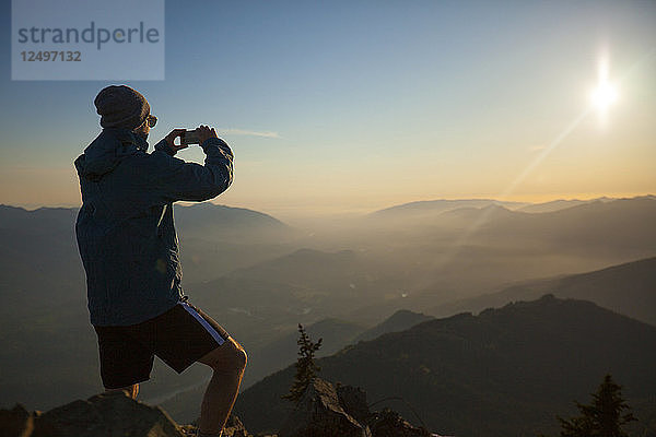 Ein Wanderer fotografiert mit seinem Smartphone die Aussicht vom Gipfel des Sauk Mountain in den North Cascades  Washington.