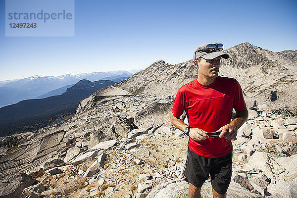 Ein Wanderer benutzt sein Smartphone  um Fotos vom Gipfel des Cassiope Peak in der Nähe von Pemberton  British Columbia  Kanada  aufzunehmen.