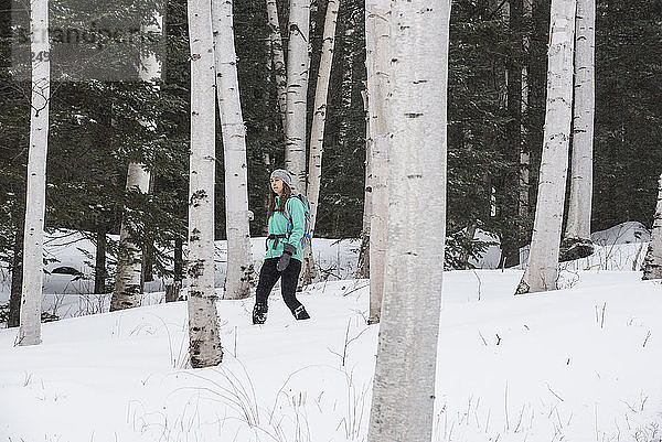 Eine Frau in einer grünen Jacke beim Schneeschuhwandern.