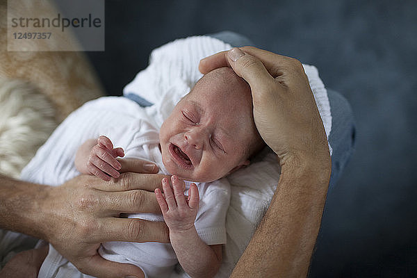 Ein Vater tröstet und tröstet sein weinendes Neugeborenes