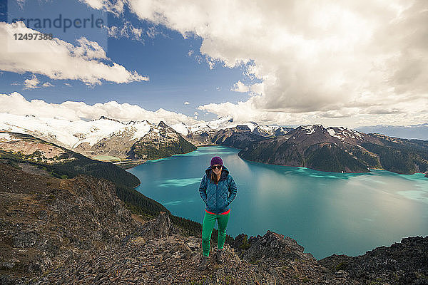 Eine Wanderin steht auf dem Gipfel des Panorama Ridge  mit dem Garibaldi Lake im Hintergrund im Garibaldi Provincial Park  British Columbia  Kanada.