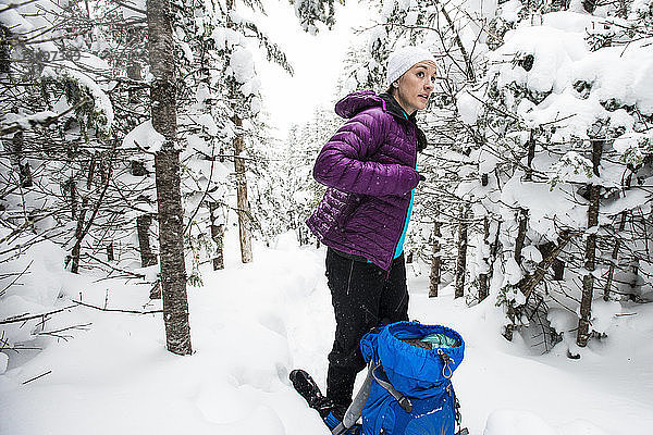 Frau beim Wandern in den schneebedeckten Wäldern von New Hampshire.