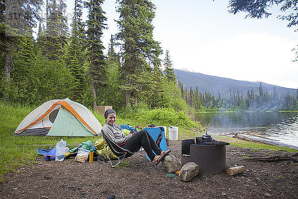 Eine Frau entspannt sich auf einem Campingplatz am See im Bowron Lake Provincial Park  British Columbia  Kanada.