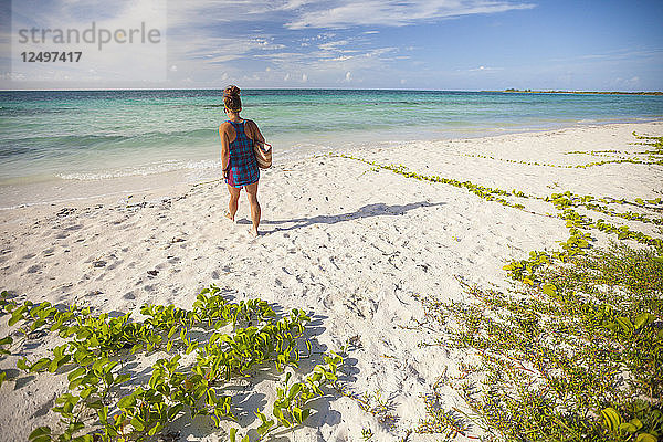 Eine junge Frau geht mit ihrer Strandtasche in Cayo Coco  Kuba  zum Meer.