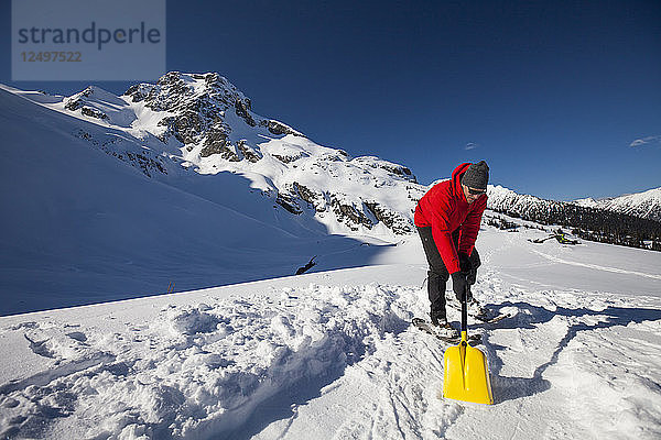 Ein Bergsteiger schaufelt Schnee  um eine flache Stelle zum Aufstellen seines Zeltes zu schaffen  während er unterhalb des Joffre Peak im Hinterland von British Columbia zeltet.