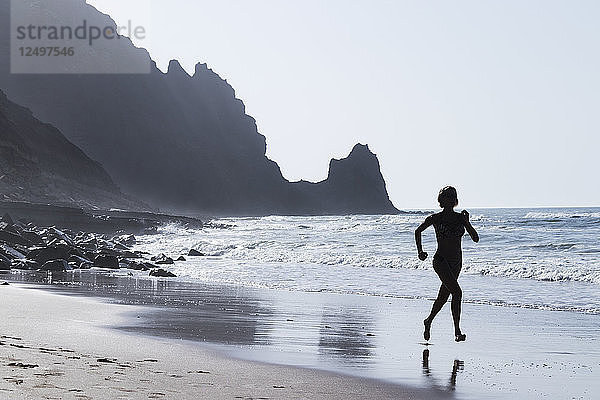 Eine Frau läuft am Strand von Luz  Portugal