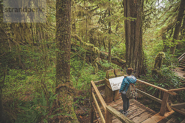 Eine Frau liest ein Hinweisschild entlang des Regenwaldpfads im Pacific Rim National Park  British Columbia
