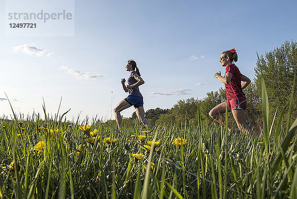 Zwei Läuferinnen laufen auf einem grasbewachsenen Feld