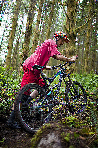 Ein Mountainbiker schiebt sein Rad auf einem Weg in North Vancouver  British Columbia  Kanada.