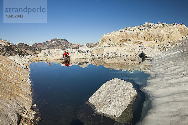 Ein Wanderer hält an  um aus einem von einem Gletscher gespeisten Bergsee in der Nähe von Whistler  British Columbia  Kanada  zu trinken.