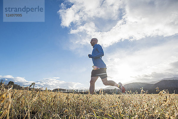 Cunchine schaut durch die Wolken  während ein Läufer durch ein Feld läuft.