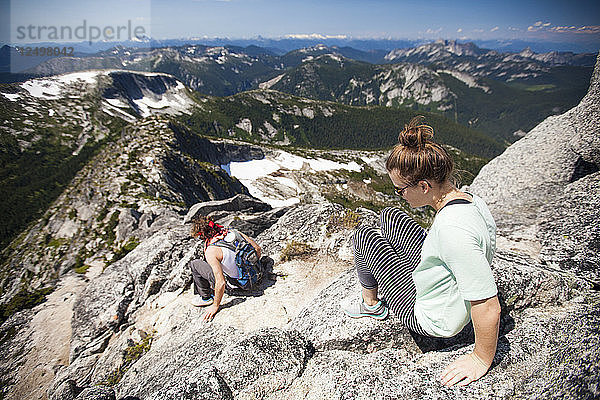 Ein junges Paar klettert auf dem Gipfelgrat des Needle Peak  British Columbia  Kanada  an Granitfelsen hinunter.