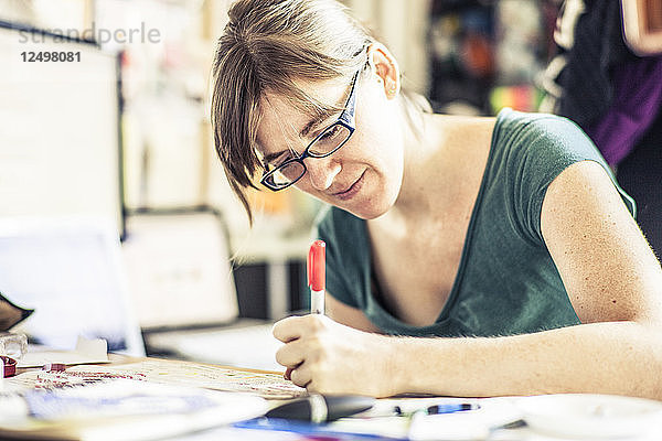 Eine Künstlerin arbeitet an einer Zeichnung in ihrem Büro zu Hause