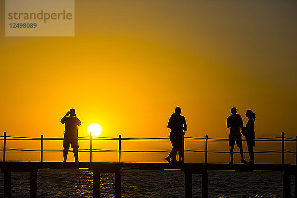 Silhouette von Touristen Menschen Erkundung Beach Resort während Sonnenuntergang