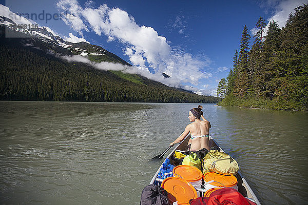 Eine junge Frau paddelt während einer mehrtägigen Kanutour durch den Bowron Lake Provincial Park über den Lanezi Lake.
