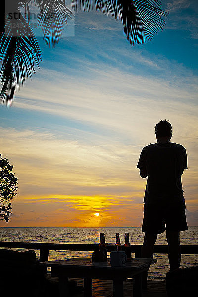Silhouette eines Mannes  der den Sonnenuntergang von einem Strand auf der Insel Koh Chang  Thailand  beobachtet