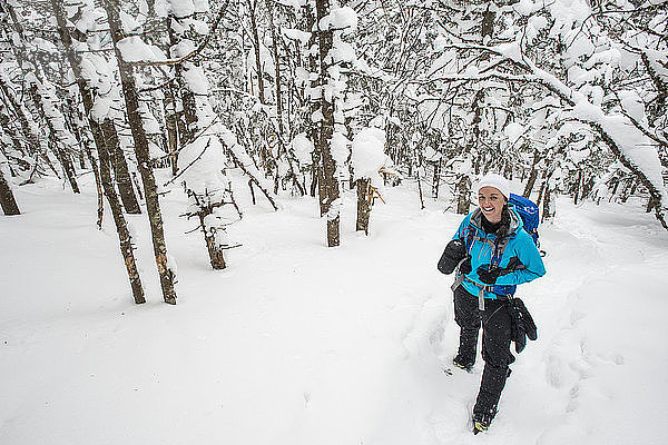 Frau beim Wandern in den verschneiten Wäldern von New Hampshire